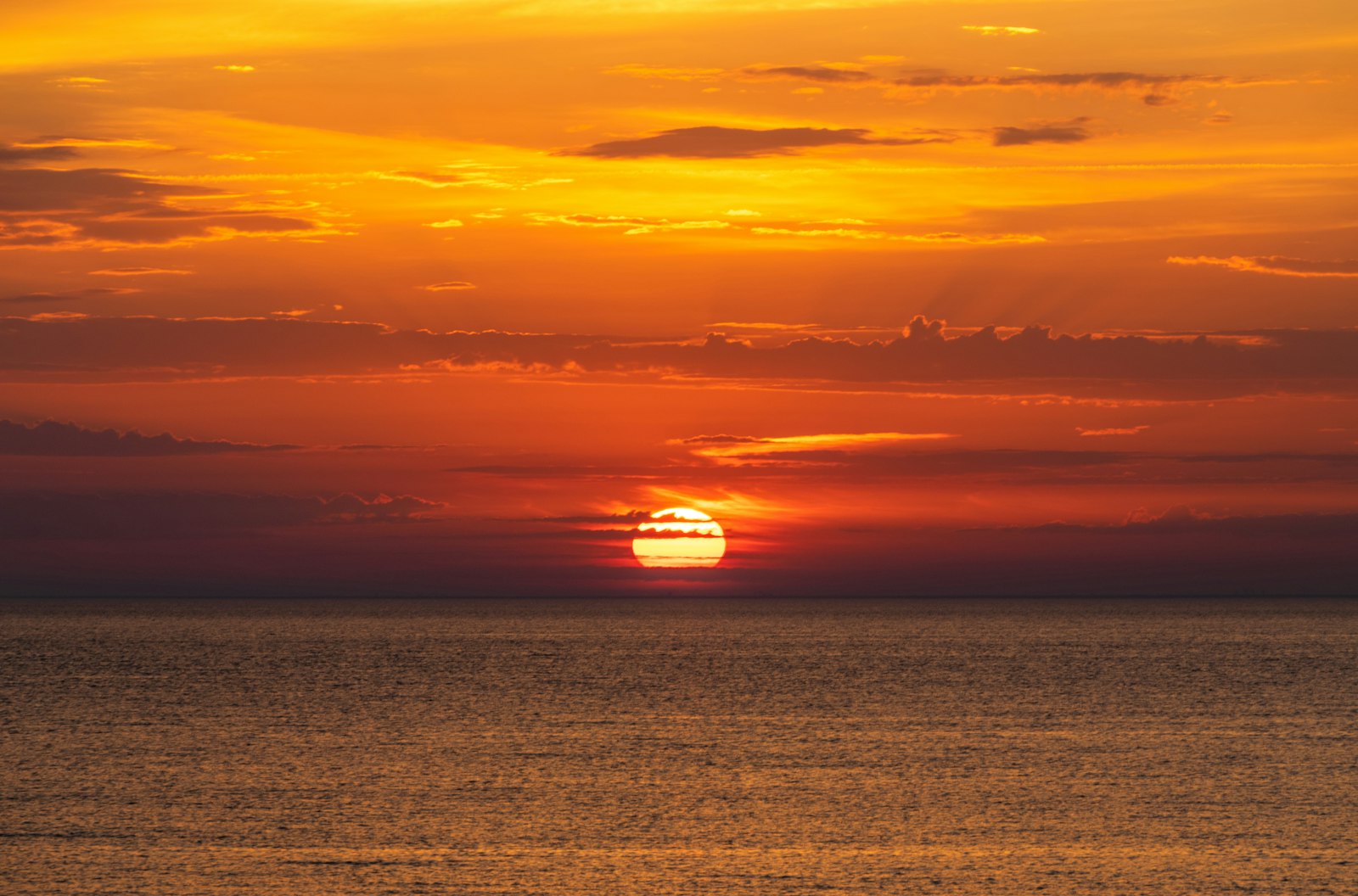 The sun setting over a calm ocean horizon